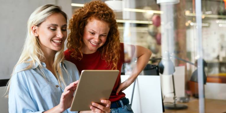 Zwei junge Frauen schauen gemeinsam auf ein Tablet